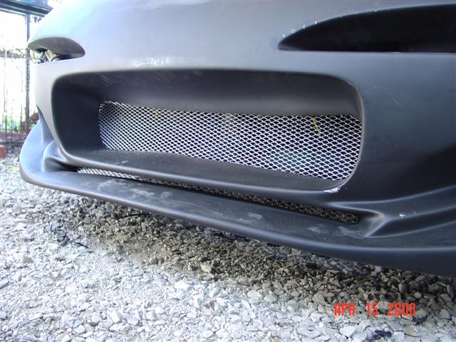 Front bumper section with a diamond mesh grille and lower lip. Watermark reads SUPERMOTORS.NET