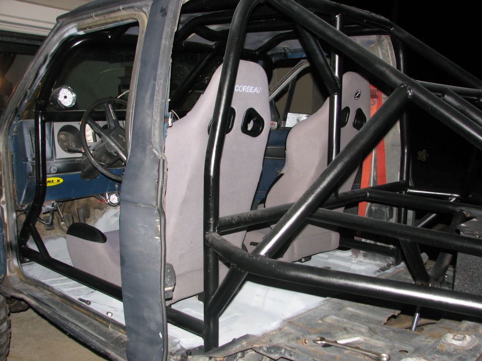 Gray Corbeau racing seats and roll cage inside a stripped-down vehicle