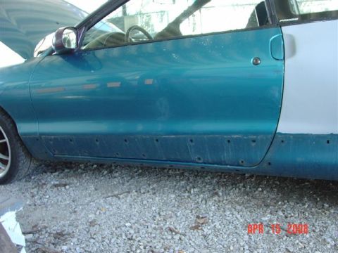 1993 Ford Probe - Side view of a teal car door, showing a primer-patched rear section and numerous holes along the lower body panel.