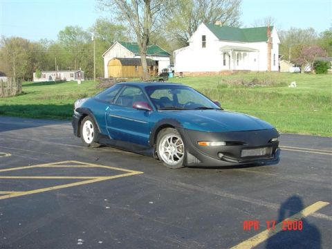 1993 Ford Probe - A blue 1993 Ford Probe is parked on asphalt with a rural house and barn in the background.