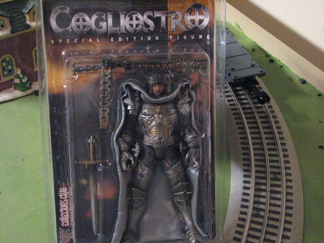 Action figure of a knight in armor, packaged with accessories, next to toy train tracks