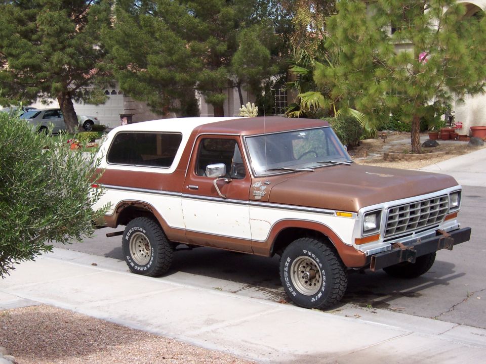 Brown and white Ford Bronco SUV with off-road tires parked on a residential street, front 3/4 view