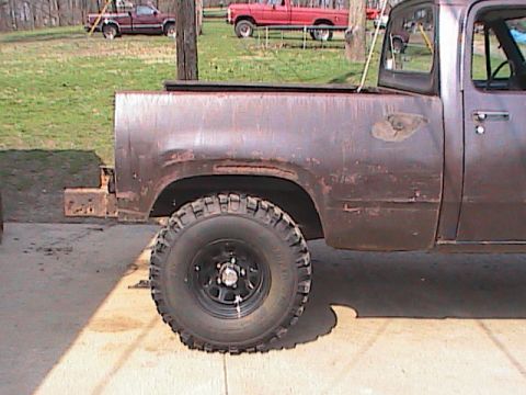 1980 Dodge Magnum - A weathered pickup truck with off-road tires is parked on a concrete surface, with other vehicles in the background.