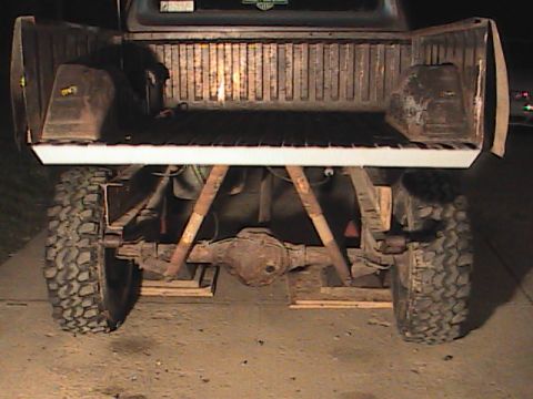 1980 Dodge Magnum - Rear view of a truck's bed and undercarriage, showing large tires and a rusty axle.