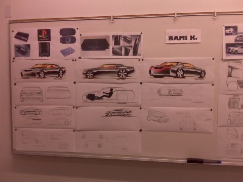 1989 Mazda MX-6 - A whiteboard displays various car design sketches and product images, including PlayStation consoles.