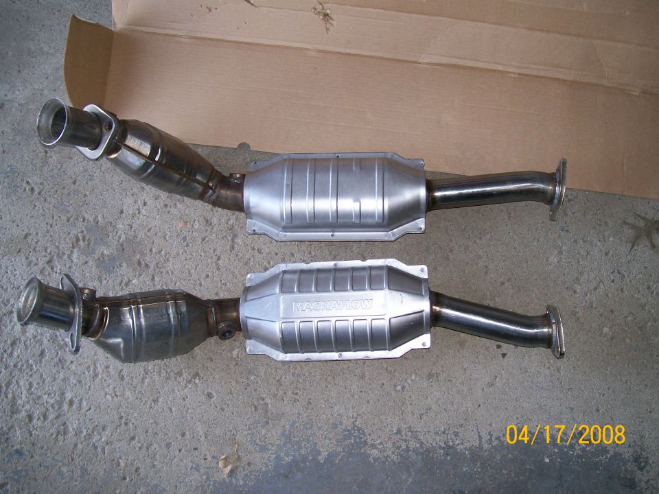 Two catalytic converter exhaust assemblies, one MagnaFlow, on cardboard