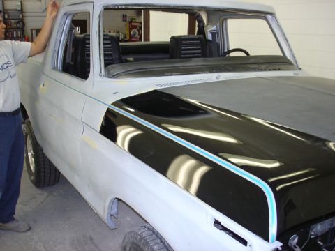 1979 Ford Bronco - A 1979 Ford Bronco is shown in primer with a black hood stripe blue trim, likely undergoing restoration.
