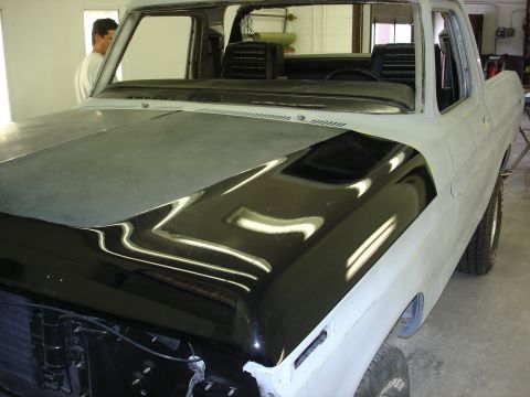 1979 Ford Bronco - Ford Bronco in primer with a freshly painted black hood, likely in a body shop.