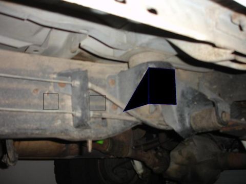 1990 Ford Bronco - Close-up view of the undercarriage, focusing on the suspension and frame components with visible markings.