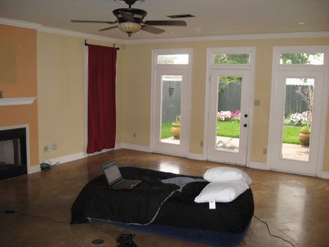 2006 Ford F-150 - A room interior features a bed with a laptop and pillows, overlooking a backyard with flowers through French doors.
