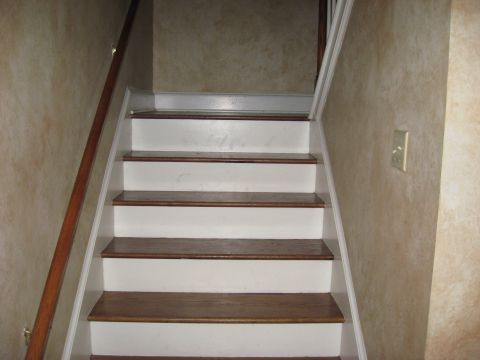 2006 Ford F-150 - A staircase with a wooden handrail and textured walls leads upwards.