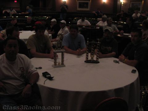 1990 Ford Bronco - group of people sit around a round banquet table displaying two trophies in a dimly lit ballroom.