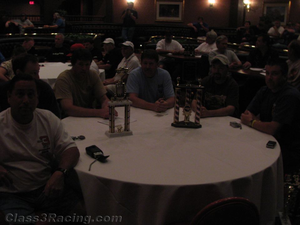 People seated around a banquet table with two trophies in a dim ballroom