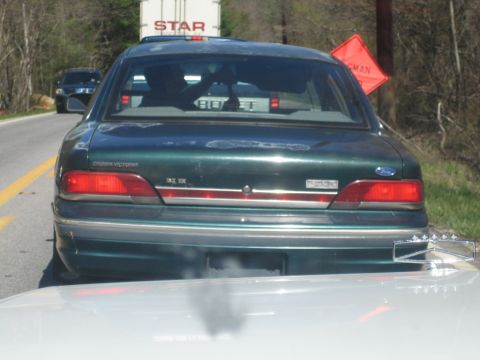 1985 Ford Crown Victoria LTD - Rear view of a green 1992 Ford Crown Victoria sedan on a road, with a truck and construction sign visible.