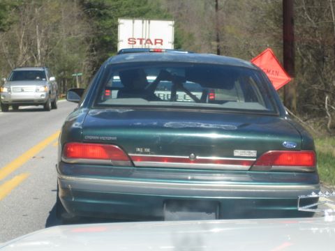 1985 Ford Crown Victoria LTD - A green Ford Crown Victoria is seen from the rear, with a silver SUV visible in the distance on a highway.
