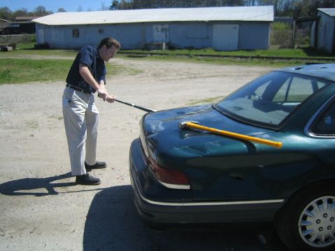 1985 Ford Crown Victoria LTD - A man is shown damaging the trunk of a car with a sledgehammer.