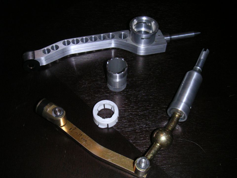 Aftermarket short shifter assembly with various components laid out on a dark surface