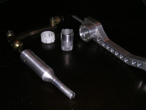 2002 BMW M3 - Several metal and plastic automotive parts, likely for a manual transmission, are arranged on a black surface.