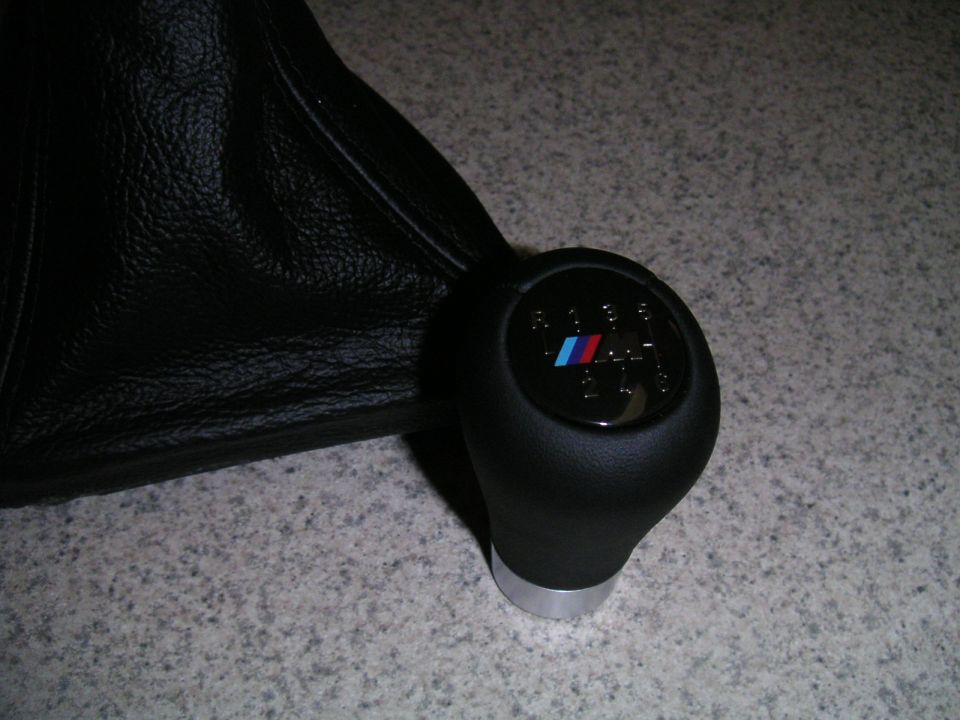 BMW M shift knob with 6-speed pattern and M logo, next to a black leather boot