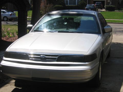 1996 Ford Crown Victoria - Front view of a silver sedan with a chrome grille and dark headlights.