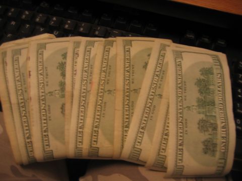 1992 Ford Mustang - A fan of US currency is displayed against a dark keyboard, with the denomination of one hundred dollars visible on each bill.