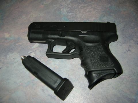 1996 Ford Bronco - A black semi-automatic pistol with its magazine lies on a textured surface.
