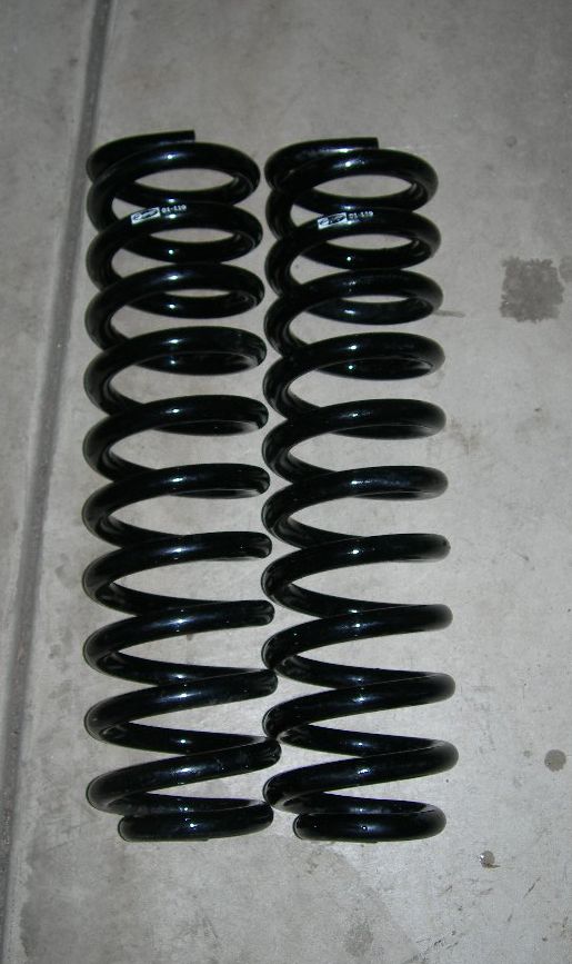 two black coil springs sitting on concrete floor, one has a white label with text