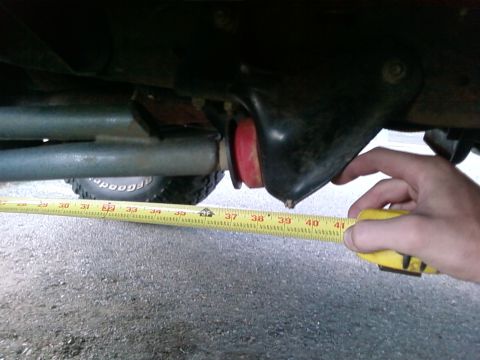 1995 Ford Bronco - A tape measure is used to measure a suspension component on a vehicle.