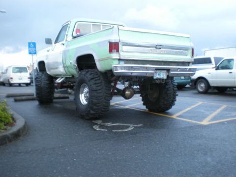 1993 Ford Bronco - This lifted pickup truck has a two-tone paint job and is parked in a lot with other vehicles.