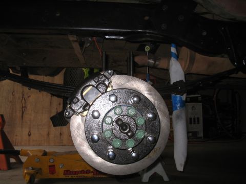 1979 Ford Bronco - Close-up of a vehicle's disc brake assembly, showing the rotor, caliper, and lug nuts.