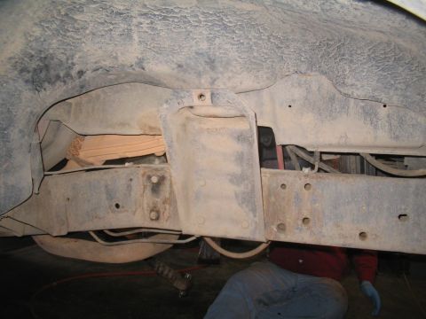 1979 Ford Bronco - Close-up of the frame and suspension system, showing various mechanical parts and a mechanic at work.