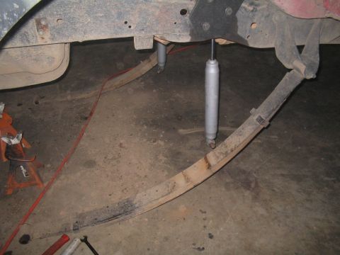 1979 Ford Bronco - The underside of a vehicle shows leaf springs and shock absorbers, likely undergoing maintenance or modification.