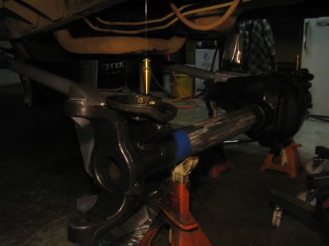 1979 Ford Bronco - The front axle assembly of a vehicle is shown supported by jack stands in a garage setting.