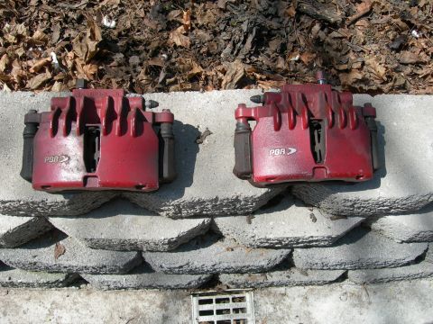 1992 Ford Taurus - Two red PBR brake calipers are displayed on a textured concrete surface.