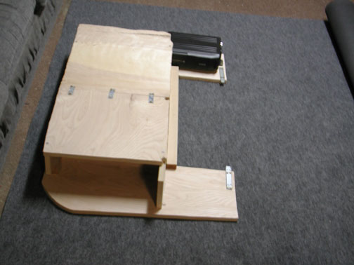 Custom plywood subwoofer box with hinged access panel and amplifier mounted on carpet