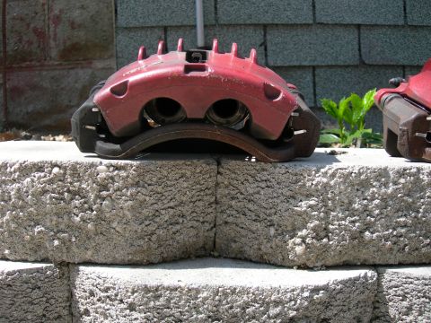 1992 Ford Taurus - A red brake caliper is shown resting on concrete blocks outdoors.