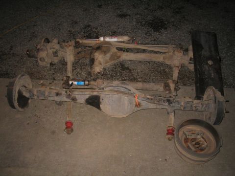 1979 Ford Bronco - Two vehicle axles are laid out on the ground, possibly for repair or modification.