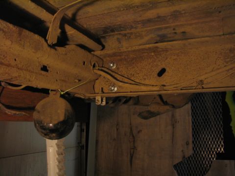 1979 Ford Bronco - The underside of a vehicle shows significant rust and a dangling spherical object.