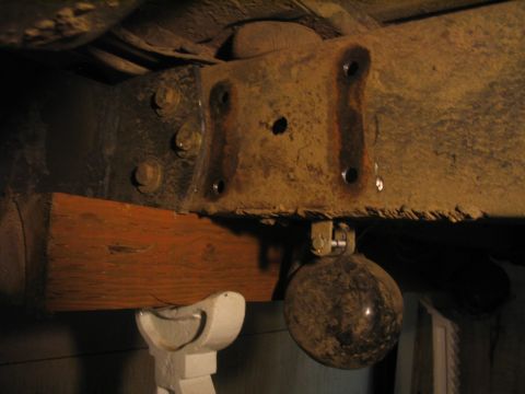 1979 Ford Bronco - Close-up view of a heavily rusted metal bracket and frame assembly, supported by a wooden block.