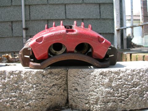 1992 Ford Taurus - A red brake caliper, likely for an upgrade, is shown resting on a brake rotor. The registry claims it is from a 1992 Ford Taurus.