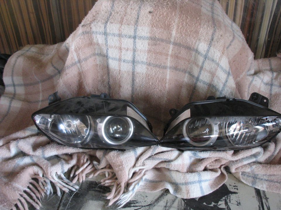 Pair of black projector headlight assemblies with halo rings on a blanket