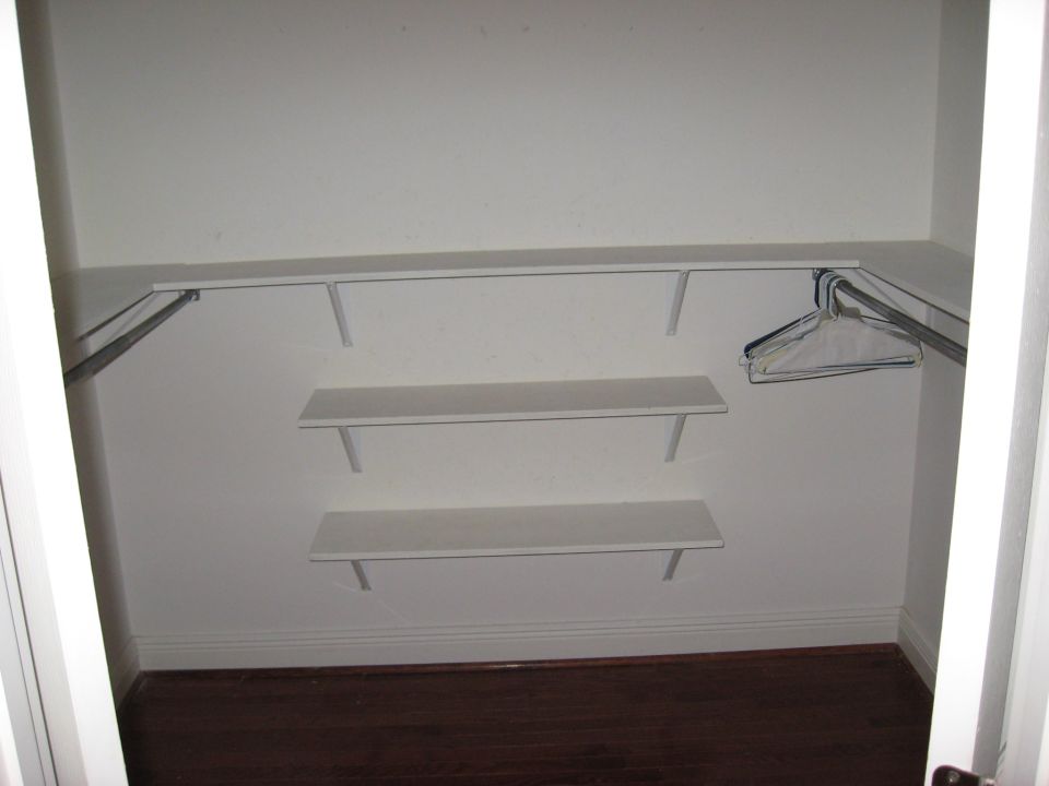 Empty closet interior with white shelves and a metal hanging rod