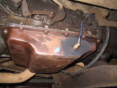 1979 Ford Bronco - Underside view of a transmission oil pan with a sensor and wiring attached.
