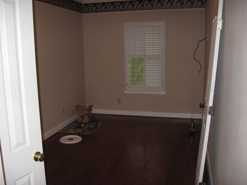 2006 Ford F-150 - An empty room with beige walls, hardwood floors, and a window covered by white shutters. A doorway is visible on the left.