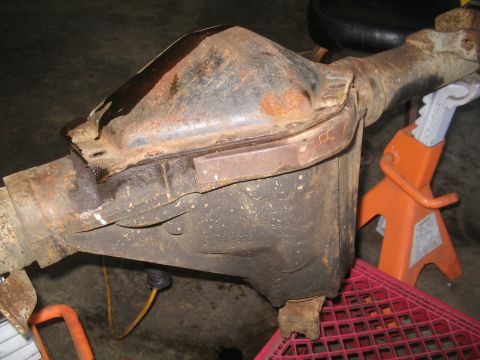 1979 Ford Bronco - A rusty rear axle differential housing is shown supported by jack stands in a garage.