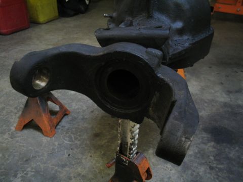 1979 Ford Bronco - A heavy black metal vehicle suspension part is supported by orange jack stands in a garage.