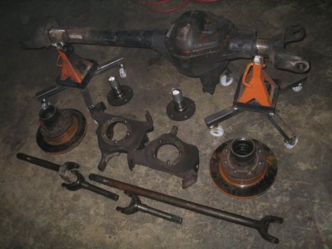 1979 Ford Bronco - Various vehicle axle and suspension components are laid out on a concrete surface.