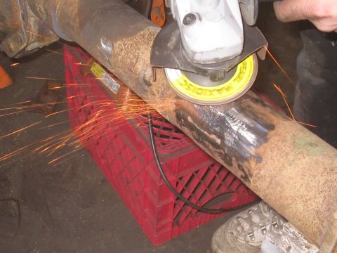 1979 Ford Bronco - Angle grinder cutting into a rusty metal pipe supported by a red milk crate.