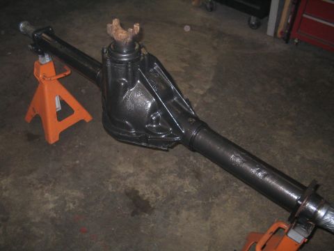 1979 Ford Bronco - A black differential axle is supported by orange jack stands on a concrete floor.