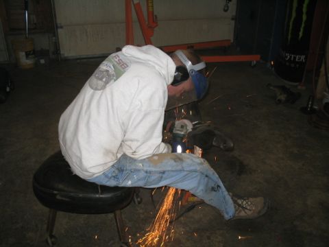 1979 Ford Bronco - A person is using an angle grinder, creating sparks in a garage setting.